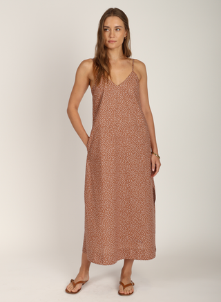 A model wearing a sleeveless, v-neck, polka dot dress in brown color.