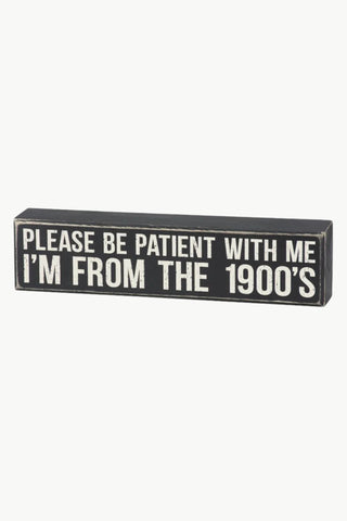 Wooden sign with text 'Please be patient with me I'm from the 1900's' on a white background
