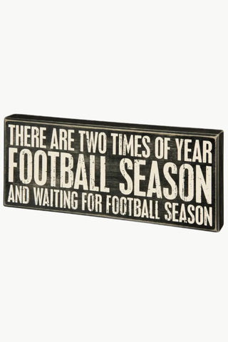 A rectangular decorative sign with a distressed black background and bold white text that reads, 'THERE ARE TWO TIMES OF YEAR FOOTBALL SEASON AND WAITING FOR FOOTBALL SEASON.'.