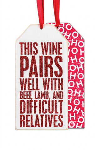 Decorative wine tag with humorous text and red ribbons on a white background
