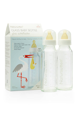 Two glass baby bottles with nipples, caps, and a product packaging box with illustrations.